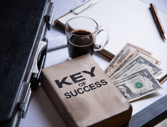 livro de título key of success sobre notas de dolares em uma mesa