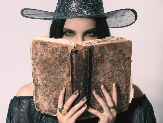 mulher segurando um livro com personagens bruxas e bruxos