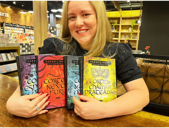 leitora segurando 4 dos 5 livros da ordem de leitura de corte de espinhos e rosas da Sarah J. Maas