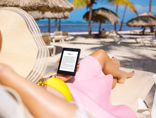 mulher lendo livros grátis no Kindle em uma praia